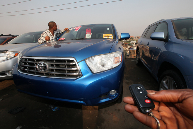 An unidentified potential car buyer test the keys of a Toyota SUV while Innocent Nwabioku who is a car dealer far left, looks at stickers on the car displayed for sale at the Berger used car market in Apapa area, Lagos Nigeria Friday 17 Dec. 2010. The Berger car market is one of the largest used car markets in Nigeria with used cars coming from the United States of America and Europe. Photo:  George Osodi for Wall Street Journal