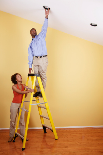 Young man standing on a ladder with a young woman standing beside him