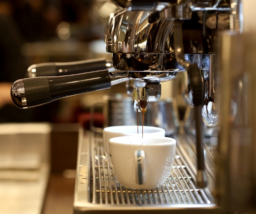 Barista prepares espresso in his coffeeshop; close-up