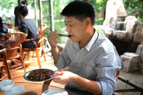JINAN, CHINA, SEPTEMBER 27, 2013: Professor Liu Yusheng from Shandong University eats fried cockroaches. Photo by Xuhua Wang.